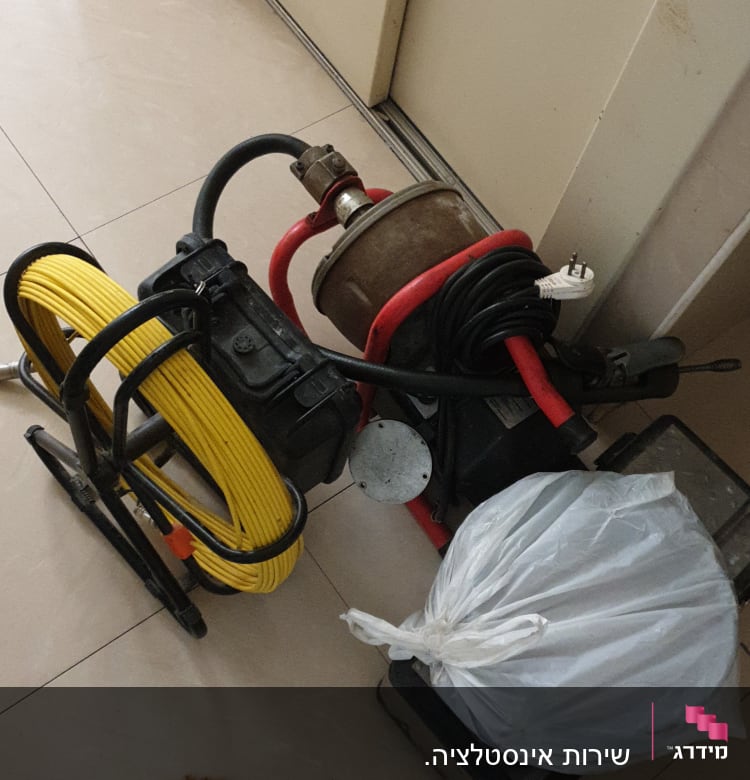 כלי עבודה של אינסטלטור עם כבל צהוב ומכונה